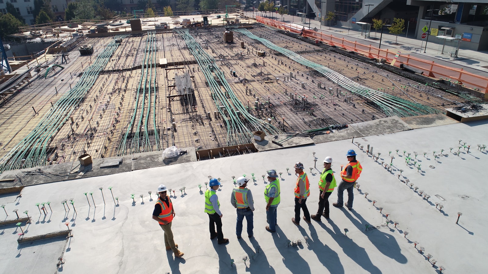 Obra em construção vista de cima, com laje, ferragem exposta e equipe de campo