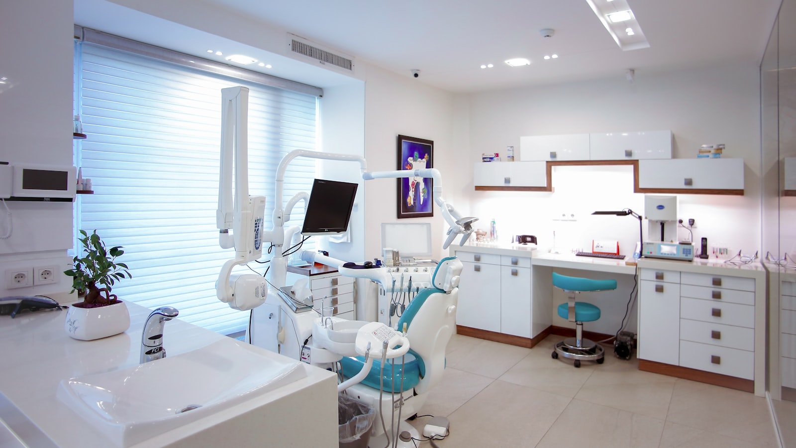 Consultório odontológico com equipamento, cadeira e bancada, em ambiente claro