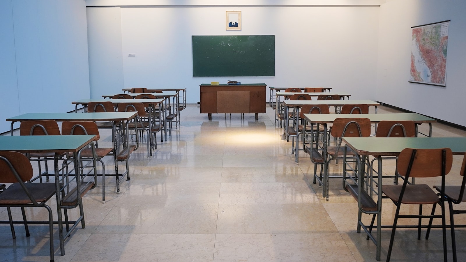 Sala de aula vazia com carteiras organizadas, lousa e mapa na parede